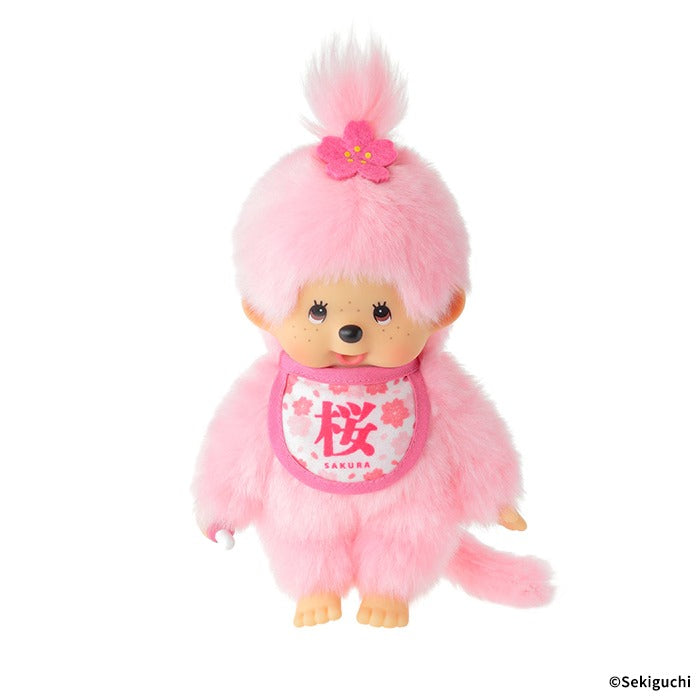 Sakura Monchhichi girl S-size plush doll, pastel pink fluffy fur, single ponytail with sakura hair clip, floral bib printed with "Sakura", Japanese spring-themed collectible toy