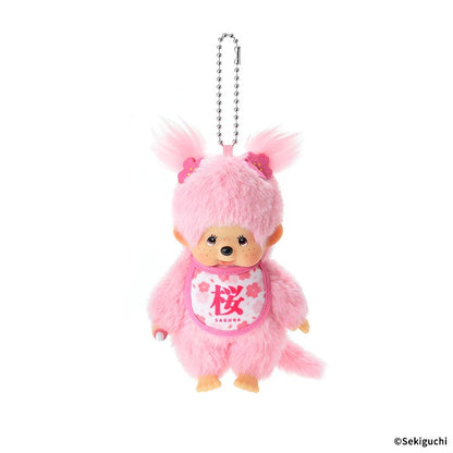 Sakura Monchhichi girl plush keychain, twin-tail design with sakura hair ornament, pastel pink fuzzy fabric, floral bib printed with "Sakura", cute Japanese spring-themed bag accessory